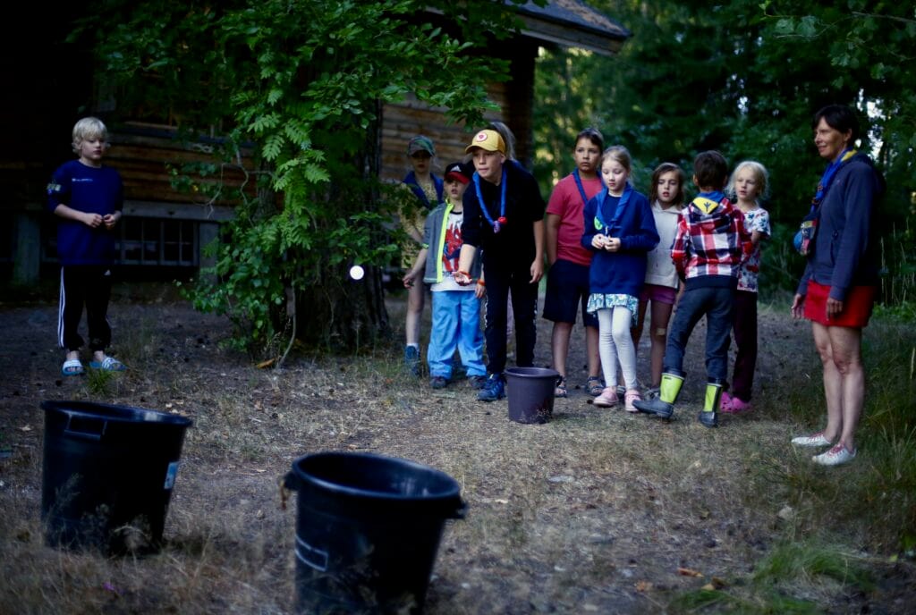 Kuva kesäleiristä ja aktiviteetista, jossa heitetään palloa ämpäriin.